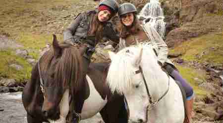 Two young females on a horse riding tour posing for photo at wilderness center iceland.